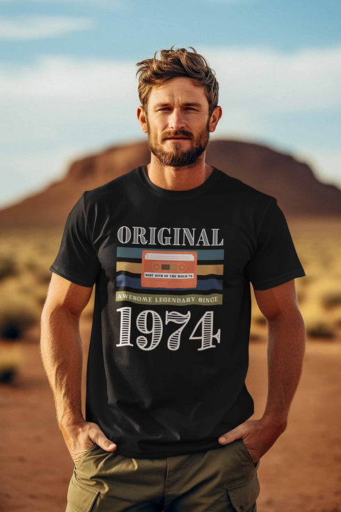 Auf dem schwarzen T-Shirt steht Original 1974. Auf dem ST-Shirt ist eine Kassette für den Kassettenrekorder abgebildet. Auf der Kassette steht Best Hits 1974